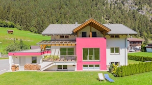 A modern two-story house with a large balcony, a separate garage, and a well-maintained lawn.