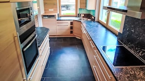 A modern kitchen with built-in appliances, a dishwasher, and a large window providing natural light.