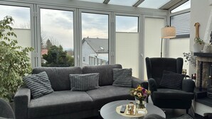 Ett modernt vardagsrum med en grå soffa, en svart fåtölj, ett runt soffbord och ett glas vatten.