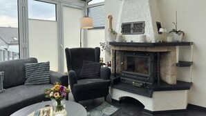 Ett modernt vardagsrum med en öppen spis, en soffa, en fåtölj och ett bord med en vas med blommor.