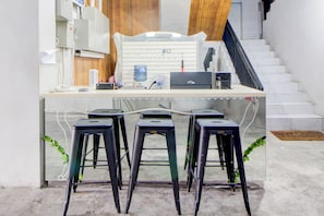 Un espacio de trabajo con un escritorio, tres taburetes, una computadora portátil y un dispensador de agua.