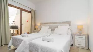 A hotel room with two beds, a wooden headboard, a small bedside table with a lamp, and a sliding glass door leading to a balcony. - Villa Placeta - Villa With Private Pool. Free Wifi (, Illes Balears)
