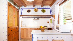 A kitchen with wooden cabinets, a white countertop, a fruit bowl, and a microwave.