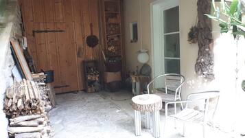 A rustic wooden door, a metal chair, a small round table, and a plant.