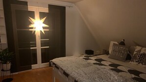 Un dormitorio con una cama, una lámpara con forma de estrella, una puerta corredera y una planta en maceta.