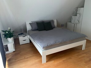 Une chambre à coucher avec un lit, des tables de chevet, une lampe, une plante et une armoire.