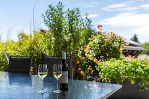 A table with two wine glasses and a bottle, surrounded by greenery and flowers. - Apartment with Large Covered Private Terrace and Wi-Fi (Allensbach)