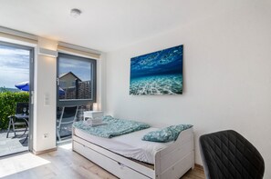 A bedroom with a bed, a chair, a window, and a painting. - Studio Apartment with Private Terrace and Wi-Fi (Allensbach)