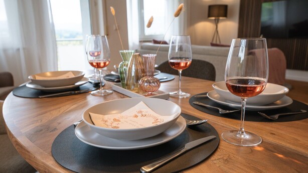 A dining table set with plates, glasses, and cutlery, with a vase and candle on the table. - Apartment 'Wohnung Im Rheintal' with Balcony and Wi-Fi (Küssaberg)