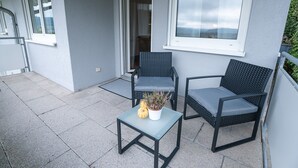 A balcony with two wicker chairs, a small table, and a potted plant. - Apartment 'Wohnung Im Rheintal' with Balcony and Wi-Fi (Küssaberg)