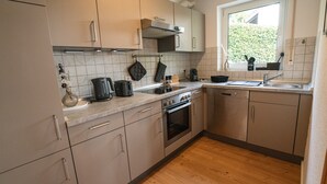 A kitchen with a stove, oven, sink, and window. - Apartment 'Wohnung Im Rheintal' with Balcony and Wi-Fi (Küssaberg)