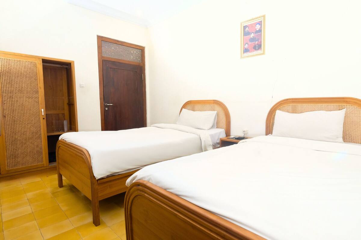 A room with two wooden beds, a wooden wardrobe, and a door with a decorative panel.