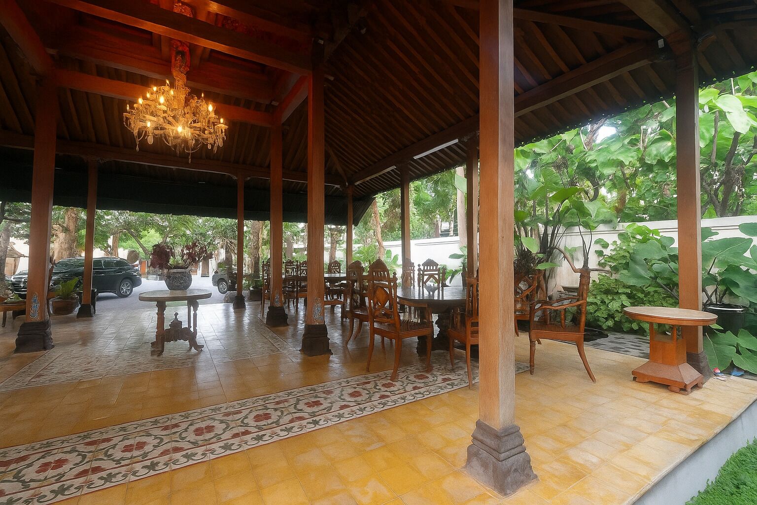An outdoor covered patio with wooden furniture and a chandelier.