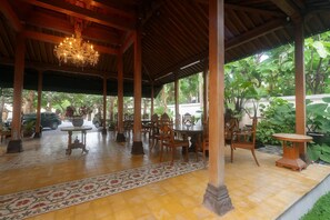An outdoor covered patio with wooden furniture and a chandelier.