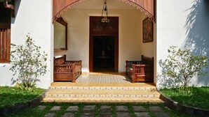 A traditional house with a wooden porch, a central door, and two wooden benches. - The Mangkoro Hotel by Sinergi (Banguntapan)