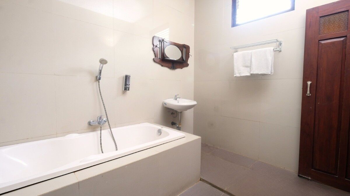 A bathroom with a bathtub, a sink, a mirror, and a towel rack.