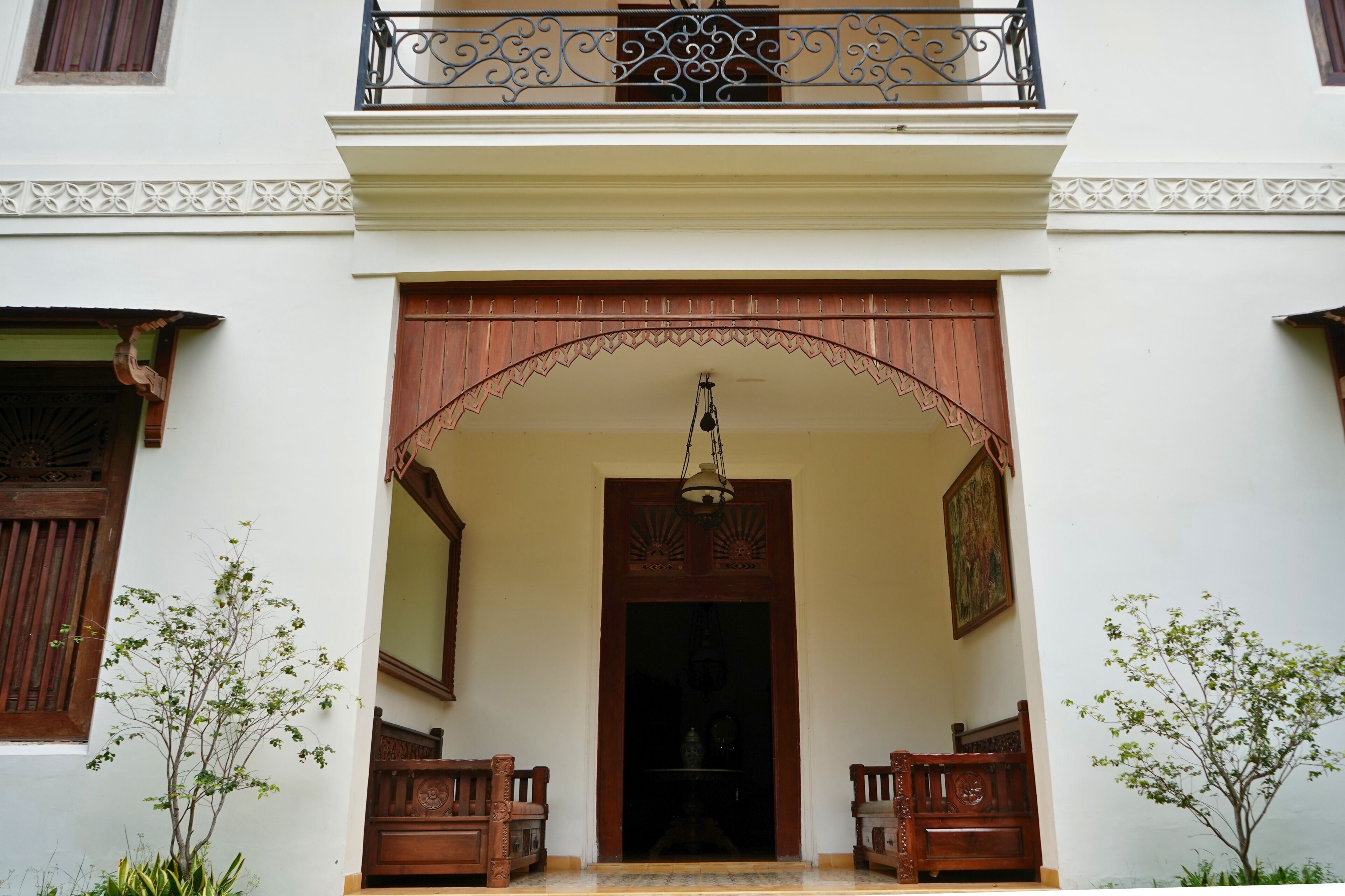 A traditional building entrance with a wooden archway, two wooden benches, and a hanging light fixture.