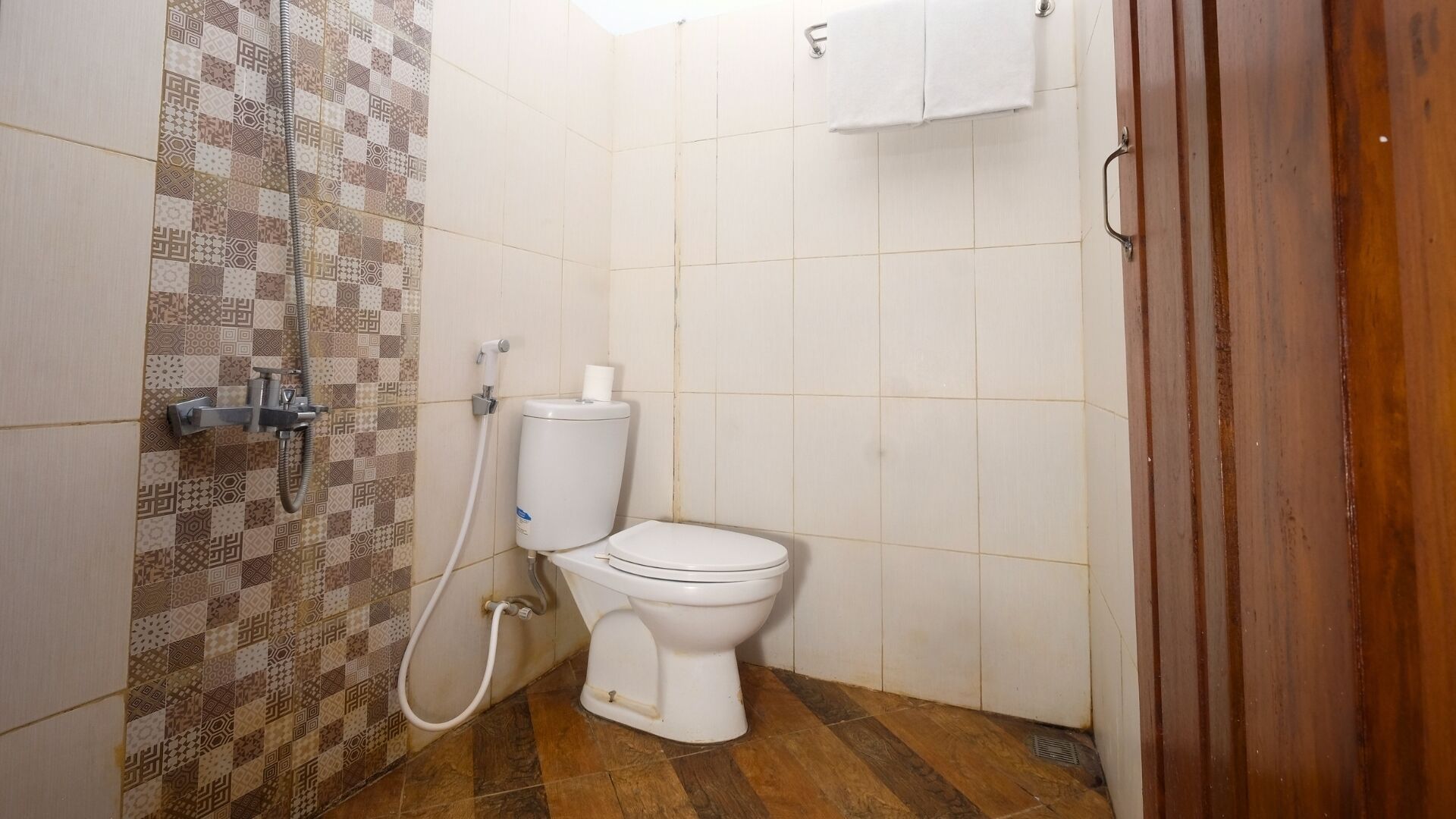 A small bathroom with a toilet, a shower, and a tiled wall.