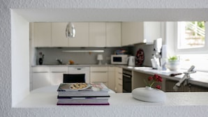 Una cucina con pensili bianchi, un forno a microonde e un vaso con fiori su un tavolo.