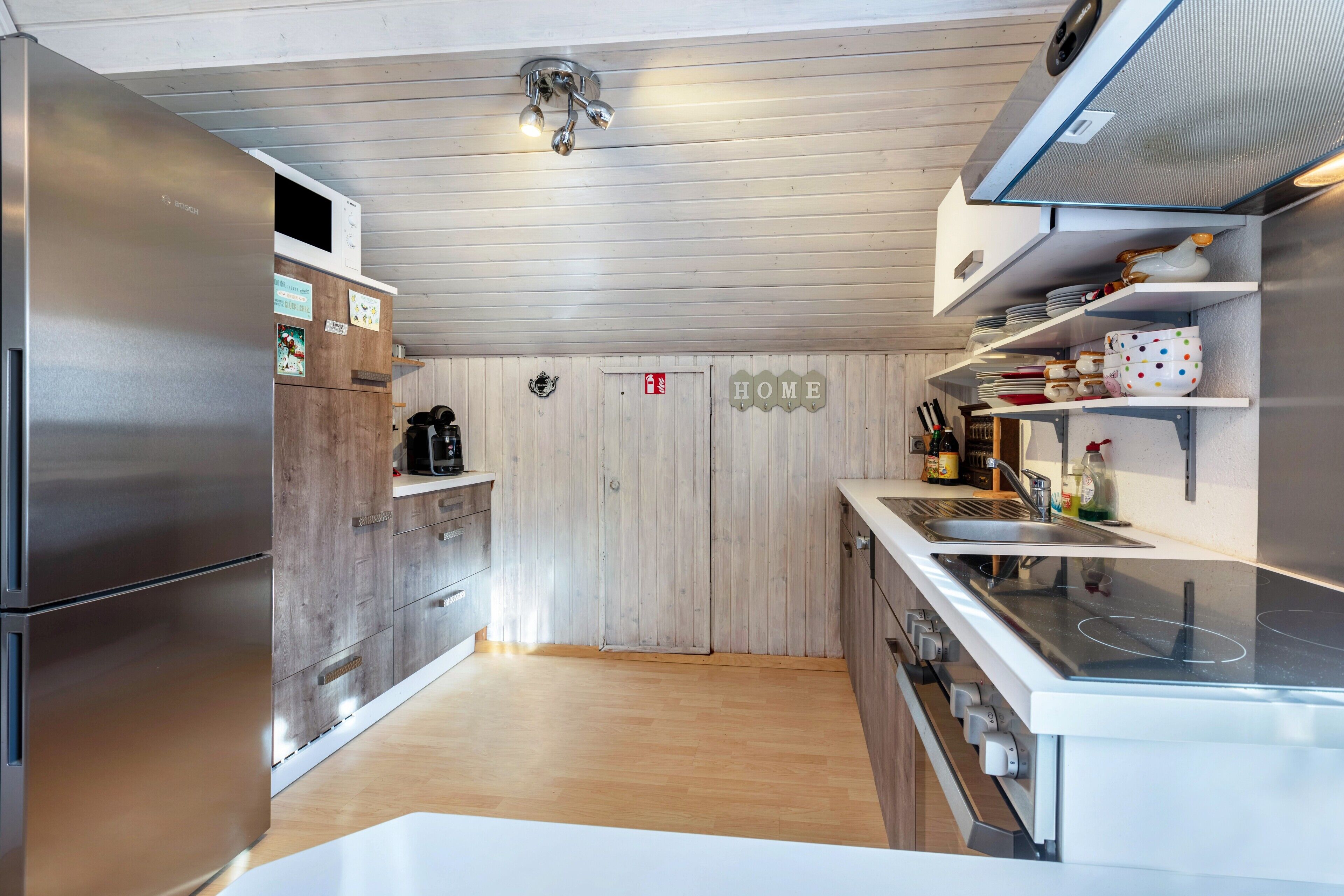 Eine moderne Küche mit Edelstahlgeräten, Holzschränken und einem Schild mit der Aufschrift 'HOME'.