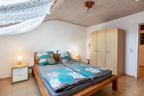 Um quarto com cama, mesas de cabeceira, guarda-roupa e ventoinha no teto.