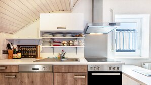 Una cocina moderna con armarios de madera, lavavajillas de acero inoxidable, horno empotrado y ventana con vistas al exterior.