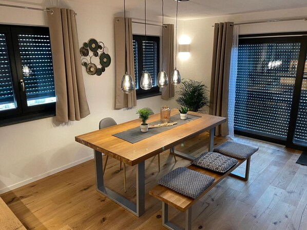 En matplats med ett träbord, bänkar som sittplatser, hängande lampor och en krukväxt.