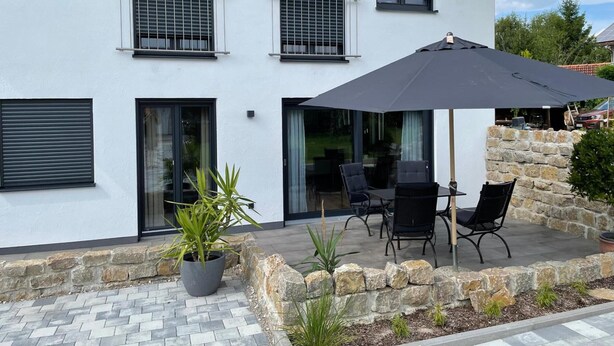 Un edificio moderno con un patio amueblado con mesas y una sombrilla grande.