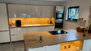 Una cocina moderna con una isla central, horno empotrado y ventana con vistas.