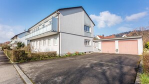Een gebouw met twee verdiepingen, een plat dak, een garage en een verharde oprit.