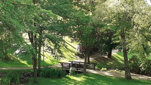 A park with a paved path, benches, and trees.