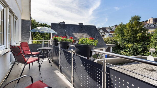 Un balcon avec une table et des chaises, des plantes en pot et une vue sur le paysage urbain.
