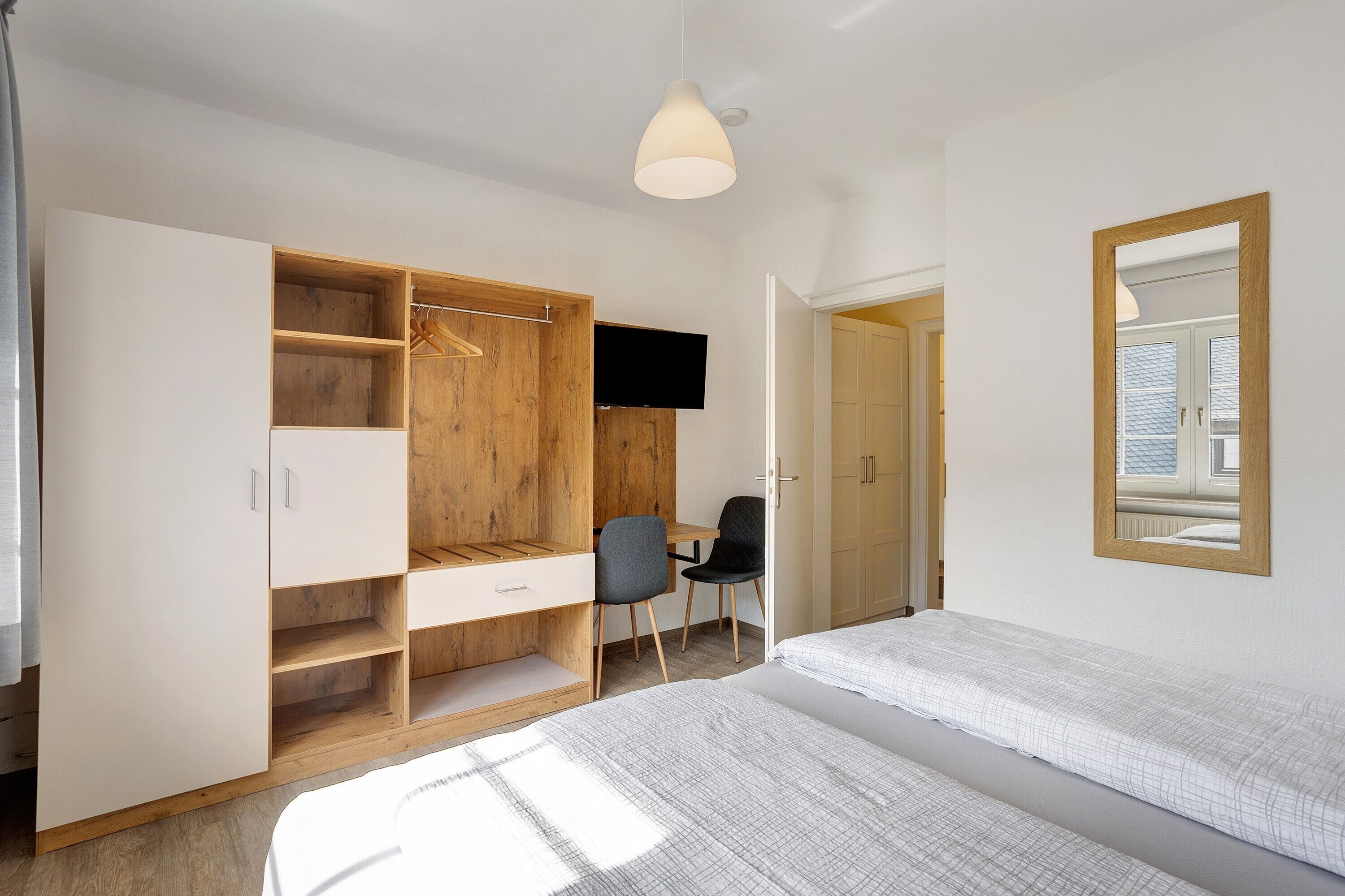 Une chambre à coucher comprenant un lit, une armoire avec plusieurs compartiments, un bureau avec une chaise et un téléviseur.