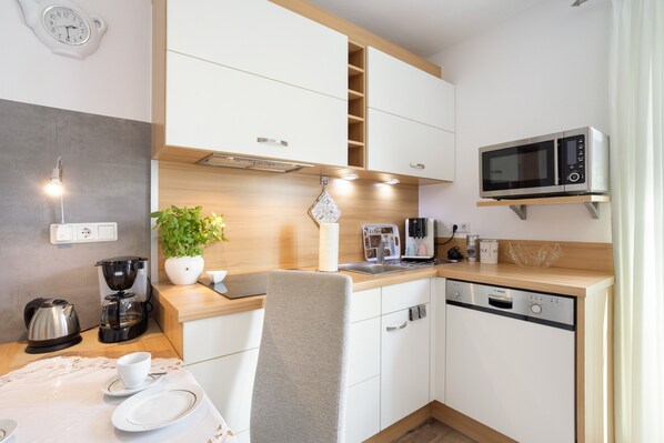 A modern kitchen with white cabinets, a microwave, a coffee machine, and a sink.
