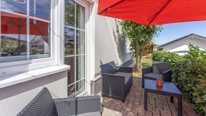 Une terrasse avec des meubles d’extérieur et un parasol rouge.