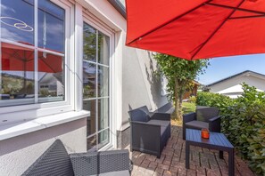 Pátio com móveis de exterior e um guarda-sol vermelho.