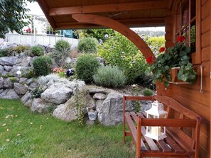 Une cabane en bois avec un mur en pierre, un banc en bois et une lanterne.