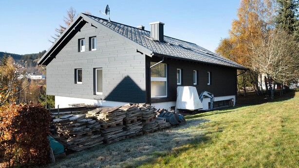 A modern two-story house with a sloped roof, a chimney, and a visible garage door.
