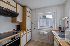A compact kitchen with a stove, coffee maker, and a window with a view.