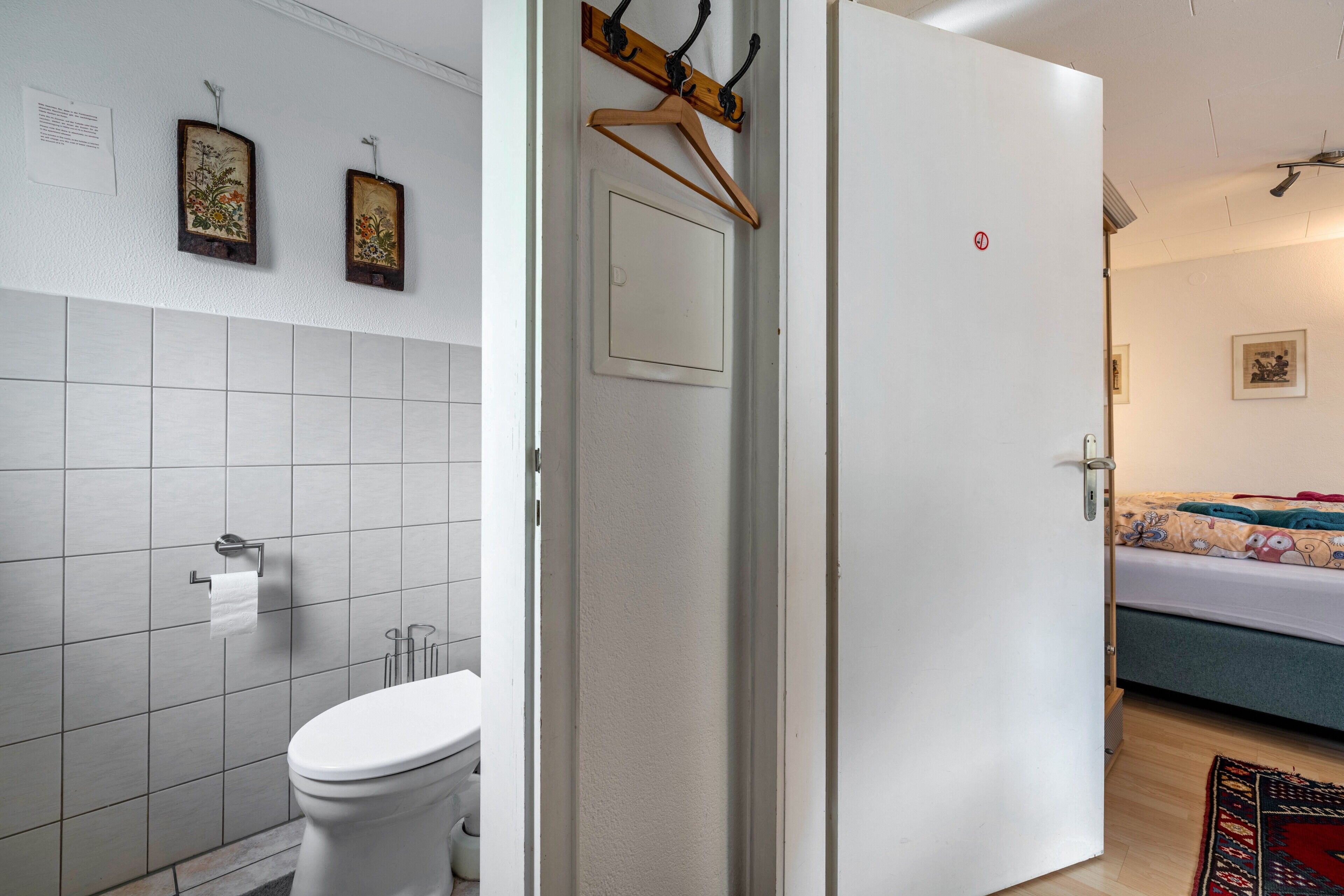 Een badkamer met een toilet, een handdoekhouder en een wandhouder voor papier.