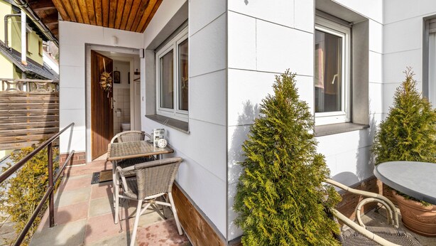 Een terras met rieten meubels, een bijzettafeltje en een kerstboom.