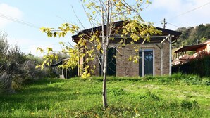 A rustic stone building with a sloped roof, surrounded by a grassy area with a small tree. - Studio in Marche With Pool Near Adriatic (Lapedona)
