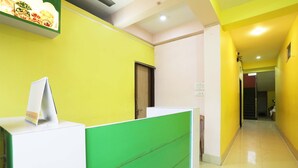 A reception area with a green and white counter, a door, and a corridor leading to another room. - Hotel Shivangi Eco TripandTrip (Puri)