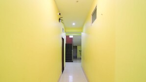 A narrow hallway with yellow walls and a tiled floor, leading to a staircase. - Hotel Shivangi Eco TripandTrip (Puri)