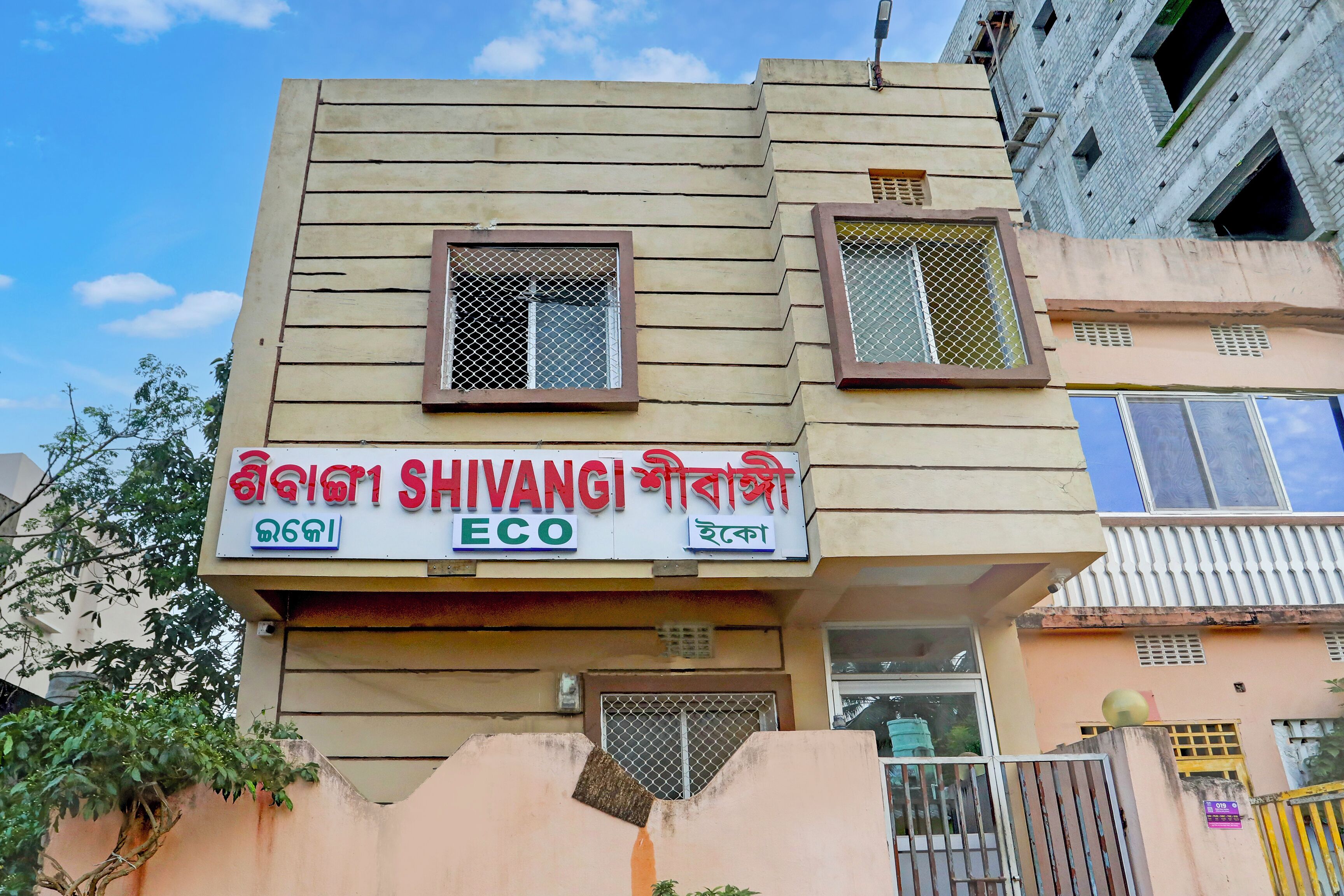 A building with a sign that reads "Shivangi Eco" in multiple languages.
