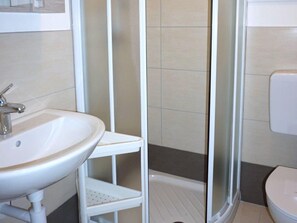 A bathroom with a white sink, a shower enclosure, and a toilet. - Apartment in Caorle Near Sandy Beaches (Caorle)
