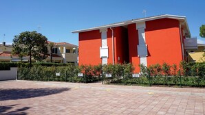 Un bâtiment rouge aux ornements blancs, entouré d’une zone pavée et de verdure.
