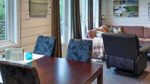 Een woonkamer met een houten tafel, twee gestreepte stoelen, een bank en een televisie.