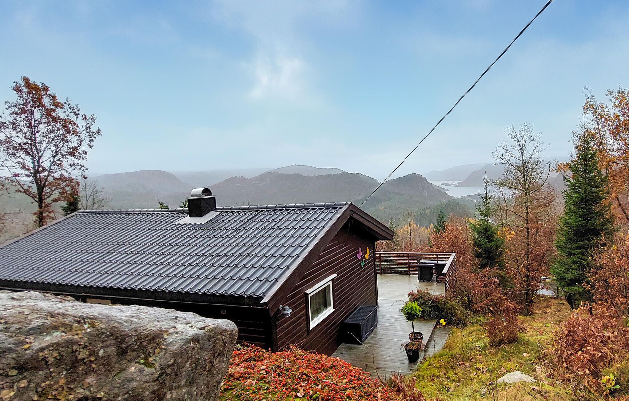 A cabin with a sloped roof, a small porch, and a view of mountains in the distance.