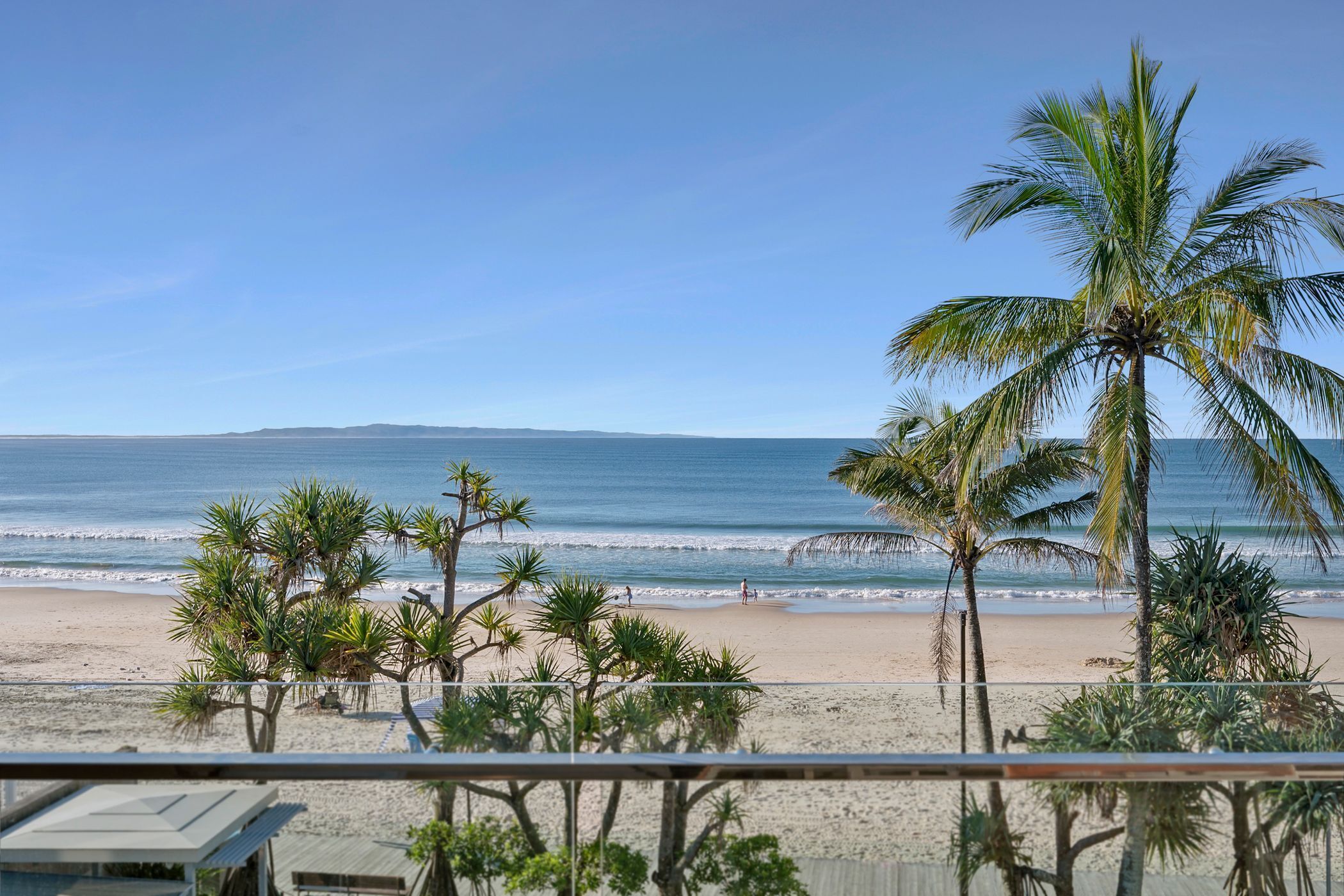 Une vue sur la plage, avec des palmiers et un ciel dégagé.